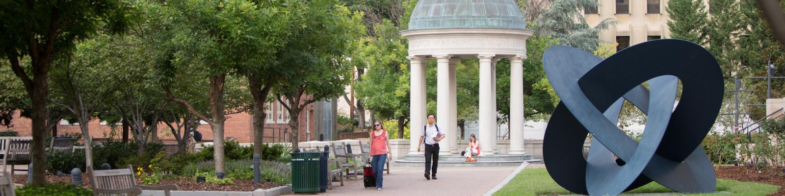 Two students walk through Kogan Plaza with the GW Tempietto in the background
